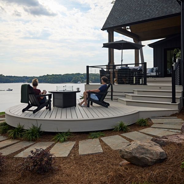 Two people sitting in the deck furniture around the Trex Fire Table on the Trex Salt Flat deck looking over Lake Wiley.